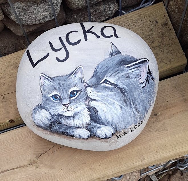Handmålad sten med katter och text 'lycka'